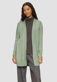 Gilet vert clair à l'avant ouvert, avec des poignets et un ourlet côtelés. Fabriqué à partir d'un matériau doux, présentant une coupe décontractée et des épaules tombantes.
