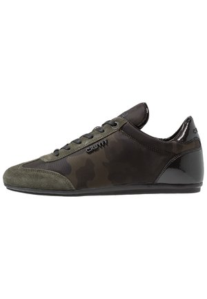 Unauffälliger Herren-Sneaker mit schwarzem und dunkelgrünem Camouflage-Muster, Wildlederspitze, glänzend schwarzer Ferse und "Cruyff"-Logo an der Seite.