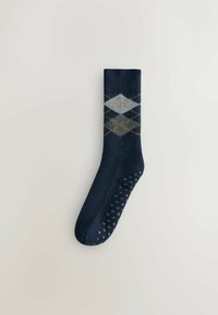 Dunkelblaue Socke mit einem Argyle-Muster, das graue Rauten und orangefarbene Akzente aufweist. Strukturiertes Fußbett mit rutschfesten Punkten für zusätzlichen Halt.
