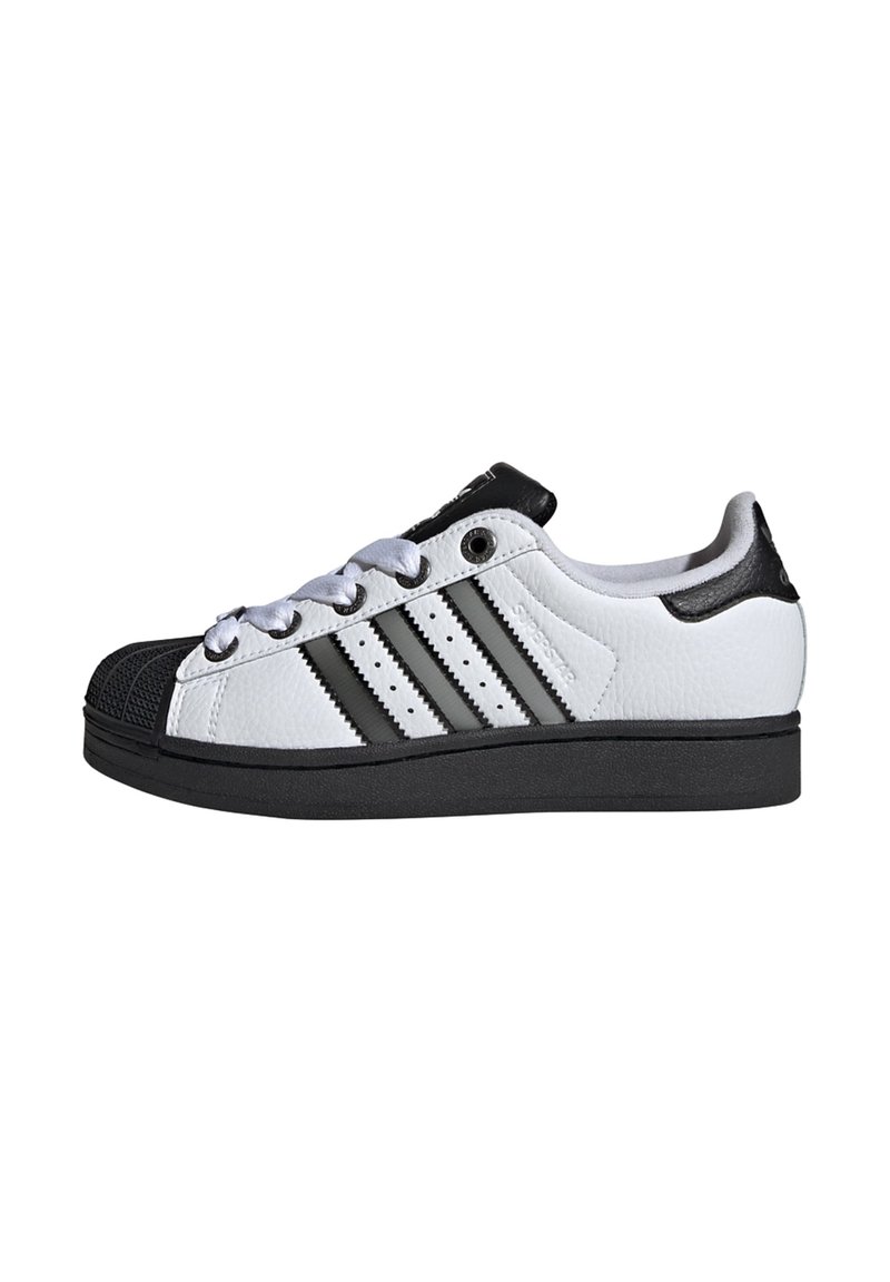 Biele kožené tenisky s čiernym gumovým špičkovým krytom a čiernymi akcentmi. Obsahujú tri čierne pruhy, okrúhle šnúrky a textúrovanú podrážku.