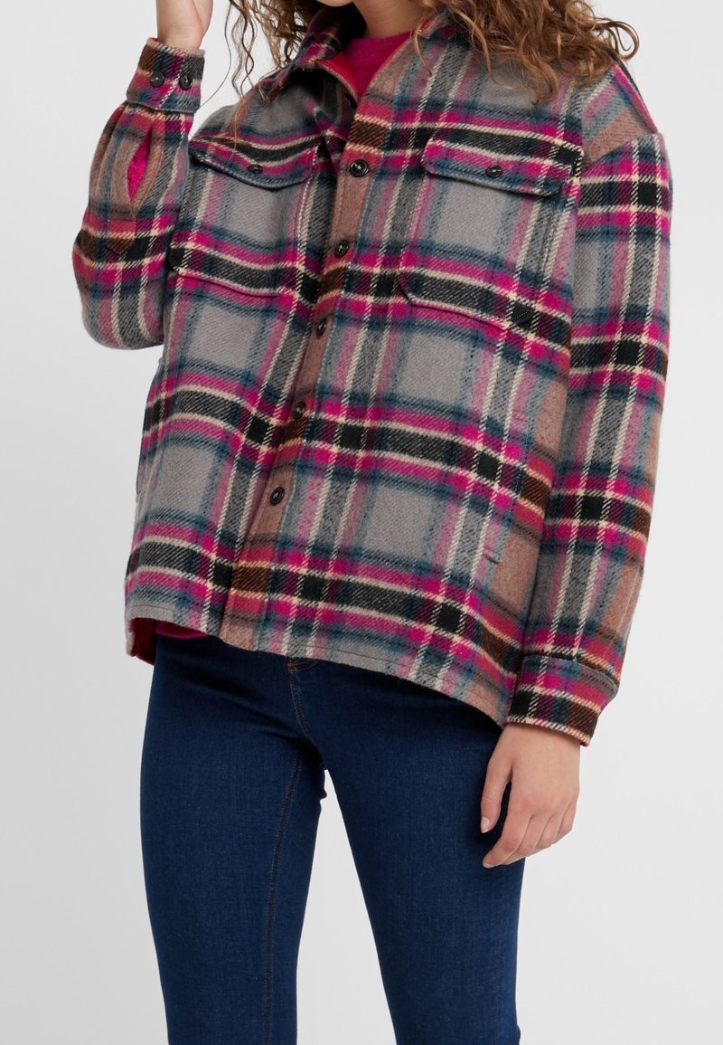 Veste en flanelle à carreaux gris, rose et noir, dotée de poches poitrine doubles, d'un fermoir à boutons et d'une coupe décontractée avec une texture douce.