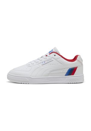 Hvid lavtop-sneaker med rødt indvendigt, blå og røde striber nær hælen og "Motorsport" label på siden, flad sål og snørebånd.