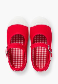 Czerwone płócienne buty typu Mary Jane z białą gumową podeszwą. Posiadają okrągły czubek, regulowany pasek oraz podszewkę w czerwono-białą kratkę.