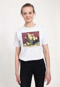 Bílé tričko s barevným potiskem misky plné pivoněk a růží, se textem ve spodní části uvádějícím název obrazu a datum.