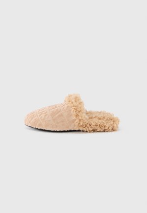 Perzikkleurige pantoffel met textuurstof en een reliëfpatroon. Pluizige nepbont voering bij de opening en een platte zool.