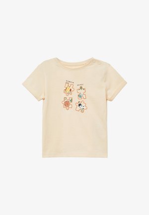 T-shirt beige pour tout-petit avec quatre pièces de puzzle représentant des animaux de dessin animé et le texte "Tu me complètes" et "Comme un puzzle !" sur le devant.