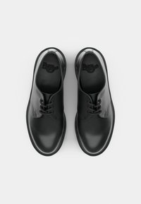 Mustat nahkakengät, joissa on pyöreä nenä, neljä silmukkaa ja sileä pinta. Pohjalliset ovat kohokuvioidulla brändillä. Tasainen kumipohja.