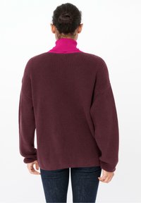 Jersey de punto en burdeos, con un alto cuello rosa y un ajuste holgado y oversize. Presenta una textura acanalada y costuras de hombro caídas.