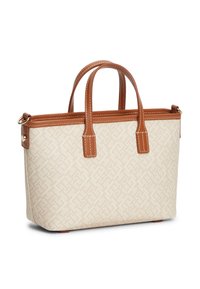 Μπεζ τσάντα tote με καφέ δερμάτινες λαβές και επένδυση, διαθέτοντας διακριτικό γεωμετρικό μοτίβο και μεταλλικούς δακτυλίους σε χρυσό τόνο στις πλευρές.