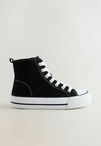 Mustast lõuendist kõrge säärega toss, millel on valged silmused, paelad ja kummist tald kontrastse varbaosaga. Lihtne õmbluse detail.