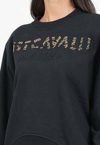 Felpa nera con testo in rilievo "CAVALLI MILANO" e design testurizzato. Collo a giro e polsini a costine. Tessuto liscio con vestibilità casual.