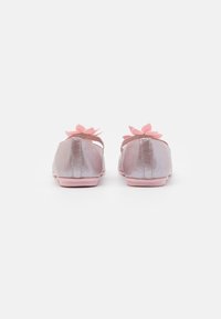 Ballet flats rose et argent avec une texture brillante, ornées d'accents de fleurs roses à l'arrière et d'un design de semelle plate et simple.