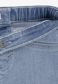 Ζώνη από ανοιχτό μπλε τζιν με μεταλλικό γάντζο και εμφανείς ραφές, κοντ ινή λήψη.