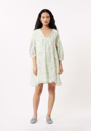 Robe légère à motifs avec un décolleté en V, des manches ballons et un ourlet asymétrique dans des teintes pastel de vert, jaune et blanc.