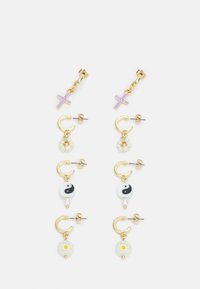 Brincos em tom de ouro com um cruz roxa, símbolo yin-yang, flores brancas e detalhes em pérolas. Vários designs disponíveis em estilos de argola e com pingentes.