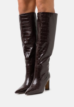 Třísťové kozačky pod kolena z tmavě hnědé kůže s krokodýlím vzorem, špičaté špičky a robustní podpatky; hladká textura a přiléhavý střih.