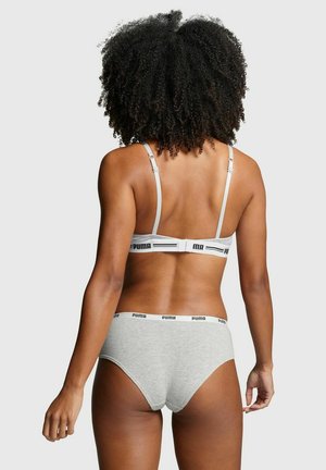 Woman with curly hair wearing gray Puma bra and matching underwear, standing facing away against a plain light background.