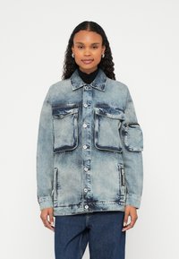 Jeans jakna v svetlo modri barvi z dvema velikima sprednjima žepoma, enim žepom za zadrgo na rokavu in zapiranjem na gumbe spredaj. Prijeten kroj, strukturiran dizajn.