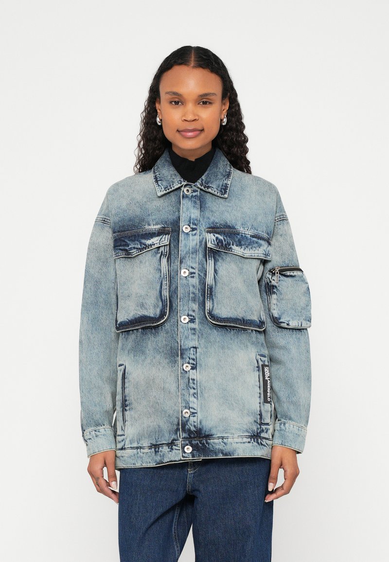 Jeans jakna v svetlo modri barvi z dvema velikima sprednjima žepoma, enim žepom za zadrgo na rokavu in zapiranjem na gumbe spredaj. Prijeten kroj, strukturiran dizajn.