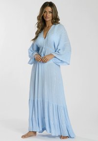 Ljusblå maxiklänning med V-ringning, vida ärmar och rynkad midja. Har en lager-på-lager kjol och en subtil glittrande detalj över hela.