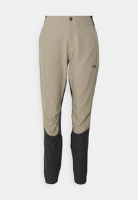 Ljusbeige byxor med mörk svarts trim, tillverkade av ett texturerat tyg. Har en knappstängning och sidofickor.