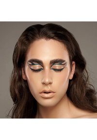 Primo piano di un volto con trucco occhi audace, turchese e nero. Pelle liscia e chiara e lunghi capelli scuri. Occhi chiusi con ciglia definite. Colore labbra neutro.