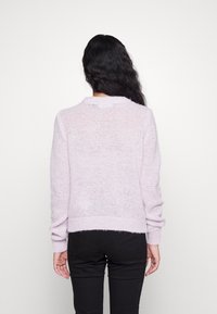 Pull en tricot lavande clair avec manches longues et poignets côtelés. Présente une coupe décontractée et une texture subtile sur toute la surface.