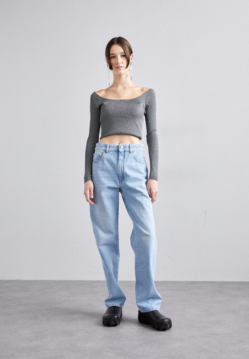 Gray ribbed crop top with off-shoulder neckline, paired with light blue high-waisted relaxed-fit jeans and black chunky platform shoes.