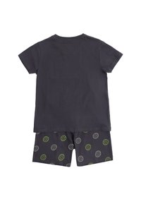 Camisa de manga corta gris oscuro combinada con pantalones cortos a juego, que presentan un patrón de diseños circulares en verde y blanco.