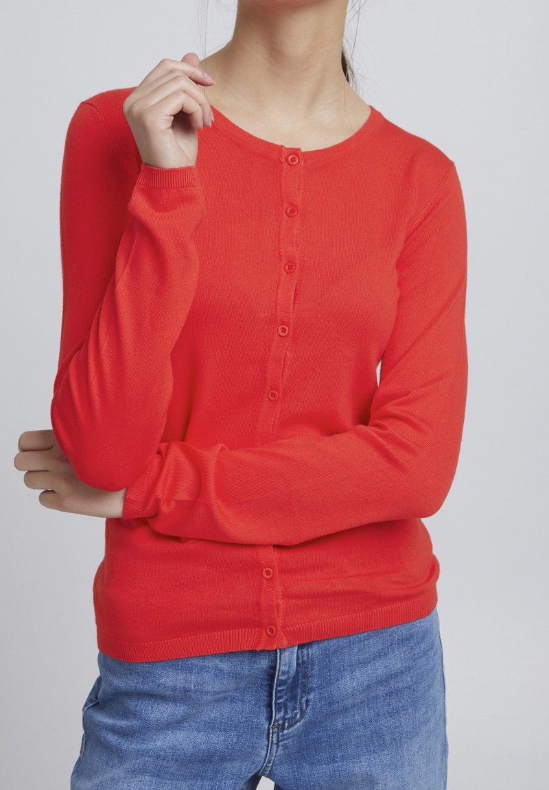 Cardigan rouge à manches longues en maille douce, avec un col rond et une fermeture boutonnée à l'avant. Texture lisse et coupe ajustée.