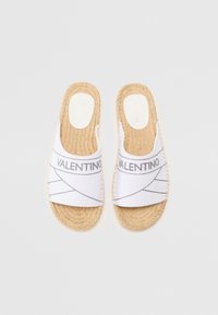 White slip-on espadrilles with a woven jute sole, featuring gray branding and geometric patterns on the fabric upper.