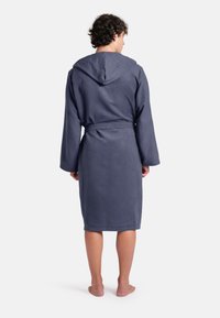 Tmavě modrý kábel s kapucí vyrobený z měkké texturované látky, s dlouhými rukávy, páskem a délku do poloviny lýtek.