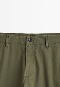 Olive zielone spodnie bawełniane z zapięciem na guzik i przeszywaną talią o teksturowanym wykończeniu. Prosty design bez wzorów i ozdób.