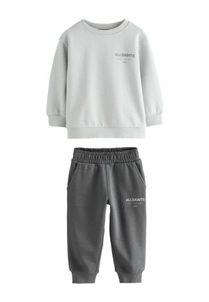Hellgrauer Sweatshirt mit gerippten Bündchen und Halsbund, kombiniert mit dunkelgrauen Jogginghosen mit elastischem Bund und Seitentaschen.