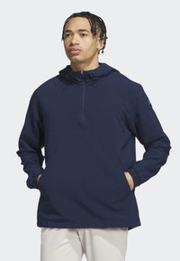 Granatowa kurtka z kapturem, z półzamkiem z przodu, elastycznymi mankietami i bocznymi kieszeniami. Wykonana z teksturowanej tkaniny, charakteryzująca się prostym, funkcjonalnym designem.