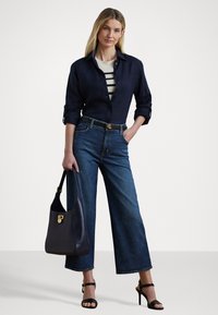 Tumši jūras zilas krāsas krekls ar pogām, uzvilkts virs krēmkrāsas un jūras zilas krāsas svītraina krekla, platajiem zilo džinsiem, melnajiem stiletto sandalēm un jūras zilas krāsas pleca somu.