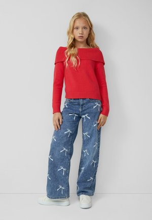 Red knit sweater with off-shoulder design; blue denim wide-leg jeans featuring white bow embroidery; paired with white sneakers.