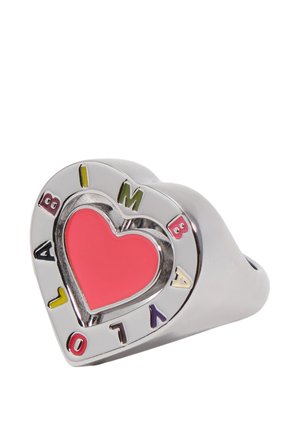 Anillo plateado en forma de corazón con un centro de corazón rojo y letras coloridas que forman la palabra "AMBIVALO" alrededor del borde sobre un fondo blanco.