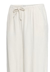 Pantalones sueltos color blanco roto de lino con cintura elástica y cordón delantero, con bolsillos laterales.