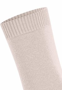 Primo piano di una calza lavorata a maglia beige con dettagli a coste sul polsino, su uno sfondo bianco.