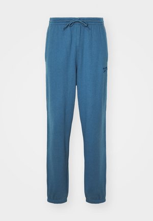 Blue, cotton sweatpants with an elastic waistband and adjustable drawstring. Features a small logo on the left leg, tapered cuffs at the ankles.