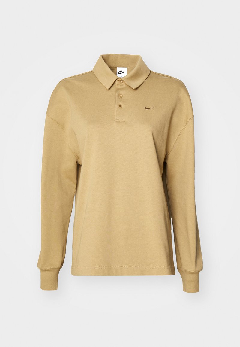 Polo shirt beige à manches longues en coton, avec un col, trois boutons et un discret logo swoosh noir de Nike.