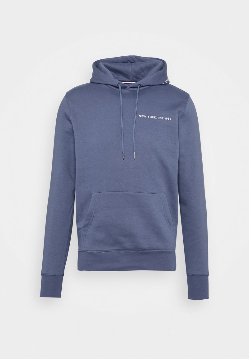 Sweat à capuche bleu avec poche avant, cordons de serrage et texte "NEW YORK, EST. 1985" sur la poitrine, présenté sur un fond blanc.