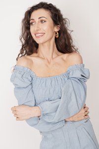 Jasnoniebieska bluzka z odkrytymi ramionami wykonana z denimu, z elastycznym marszczeniem, obszernymi rękawami i zb gathered na mankietach dla dopasowanego wyglądu.