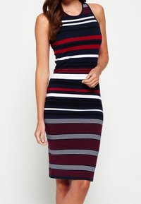 Hihaton, istuva midimekko, jossa on vaakasuoria raitoja tummansinisesssä, punaisessa ja valkoisessa. Sujuva neulekangas, jossa on ribbitekstuuri.