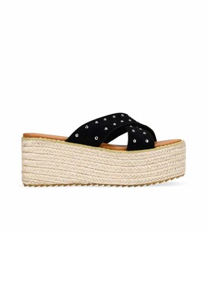 Sandalia negra tipo slide con tachuelas plateadas y suela plataforma gruesa de yute trenzado.