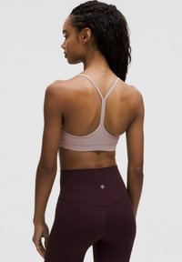 Roze sportbeha met een racerback ontwerp, gemaakt van rekbare stof. Hoogstaande donkerbordeaux leggings met een klein logo op de achterkant.