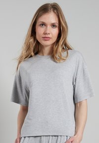 T-shirt grigio a maniche corte realizzato in un tessuto morbido e liscio. Presenta una vestibilità comoda e un piccolo logo vicino all'orlo inferiore.