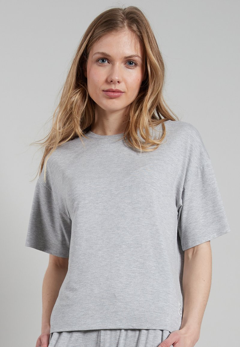 T-shirt grigio a maniche corte realizzato in un tessuto morbido e liscio. Presenta una vestibilità comoda e un piccolo logo vicino all'orlo inferiore.