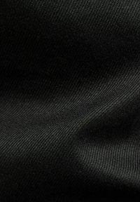 Czarna tkanina o gładkiej fakturze i gęstym splocie, z subtelnymi różnicami odcieni i światłem odbijającym się na powierzchni.